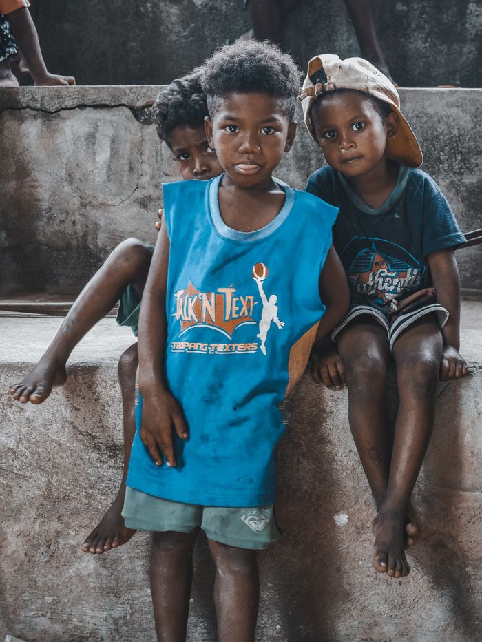 Three young boys pose on a stone structure, embodying childhood innocence and friendship.